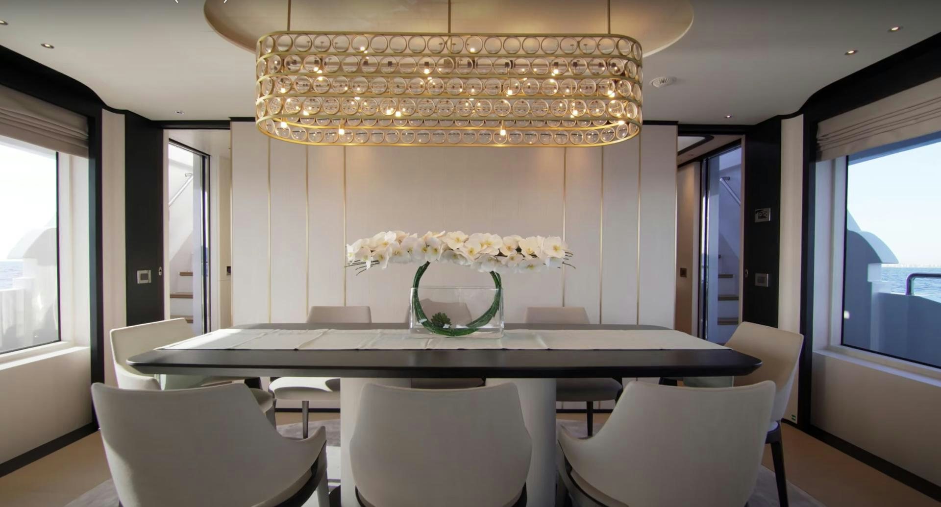a dining room table with chairs and a chandelier aboard Benetti 95 Delfino Yacht for Sale