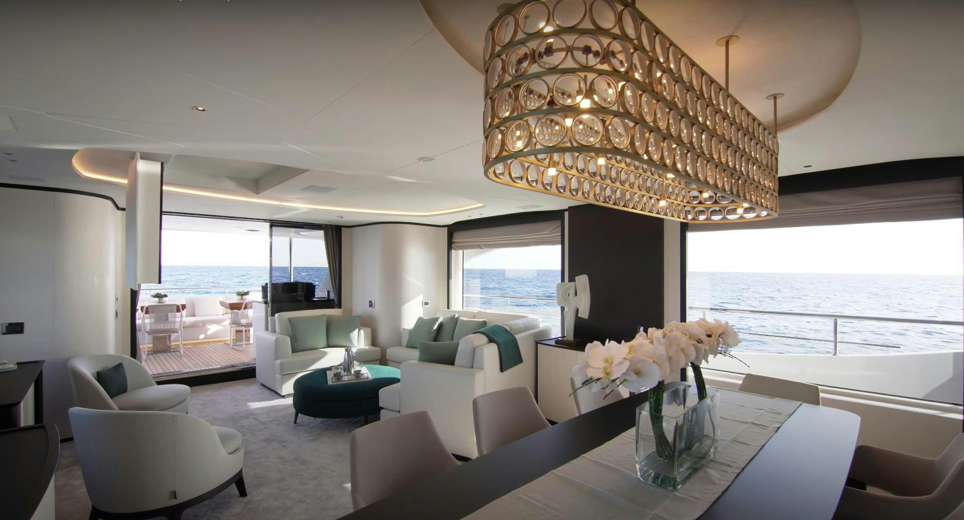 a large living room with a large chandelier aboard Benetti 95 Delfino Yacht for Sale