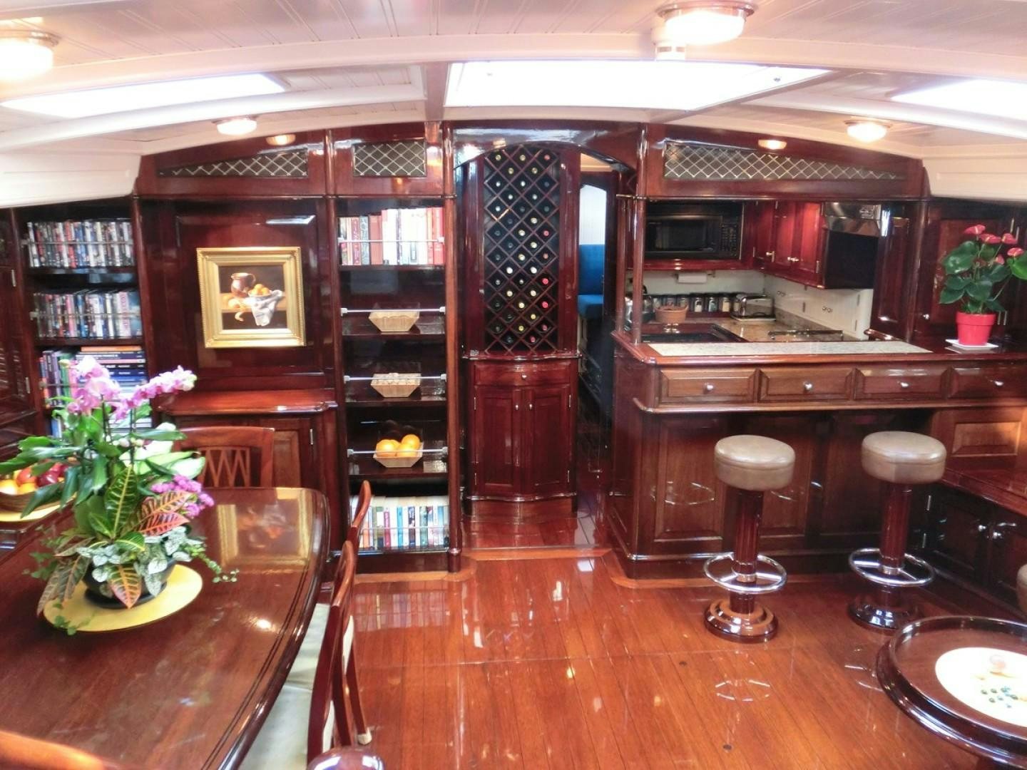 a room with a shelf and a table with chairs and a shelf with books aboard CARMELLA  Yacht for Sale