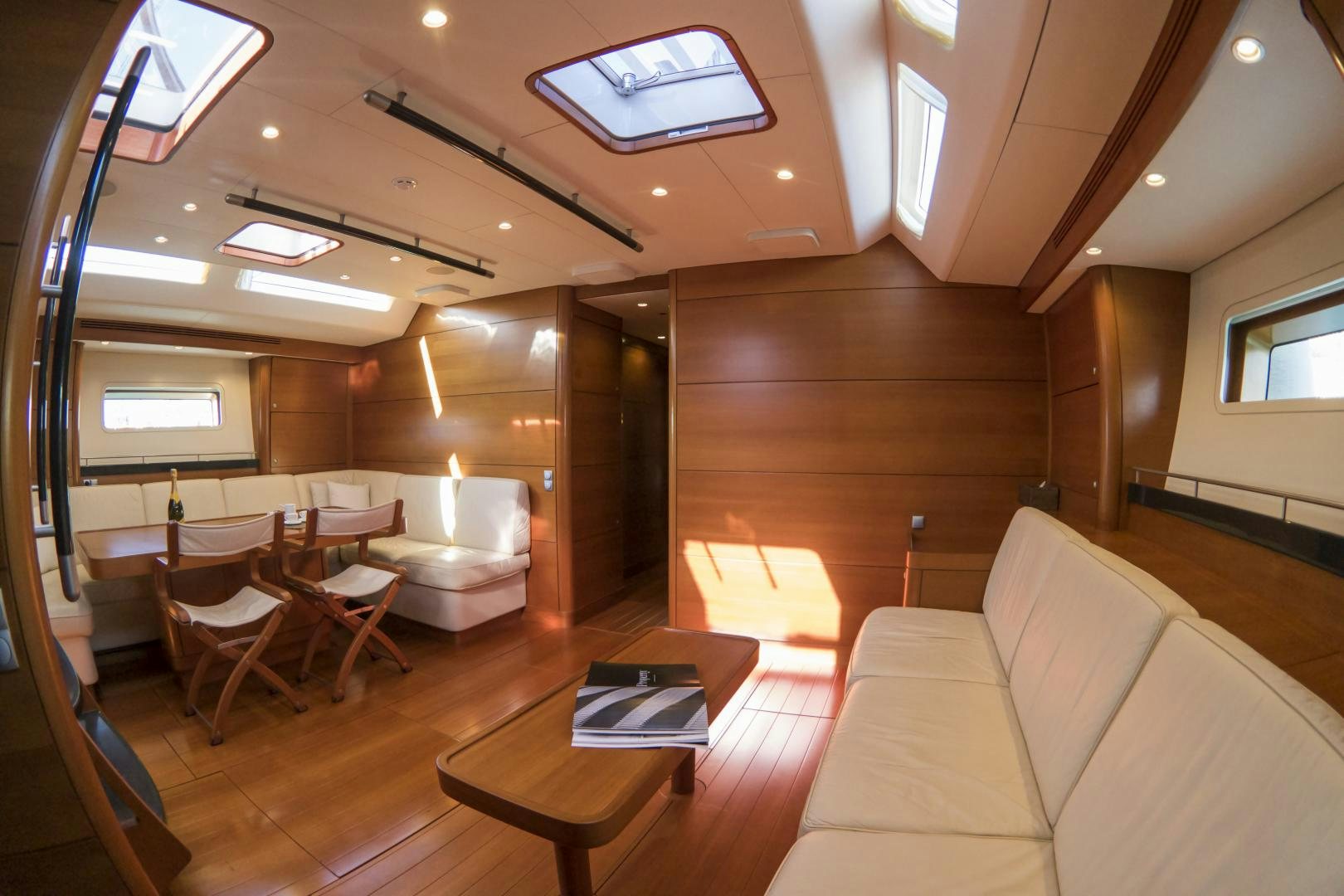 a room with a wood floor and a wood floor and a table with chairs and a couch and aboard B5 Yacht for Sale