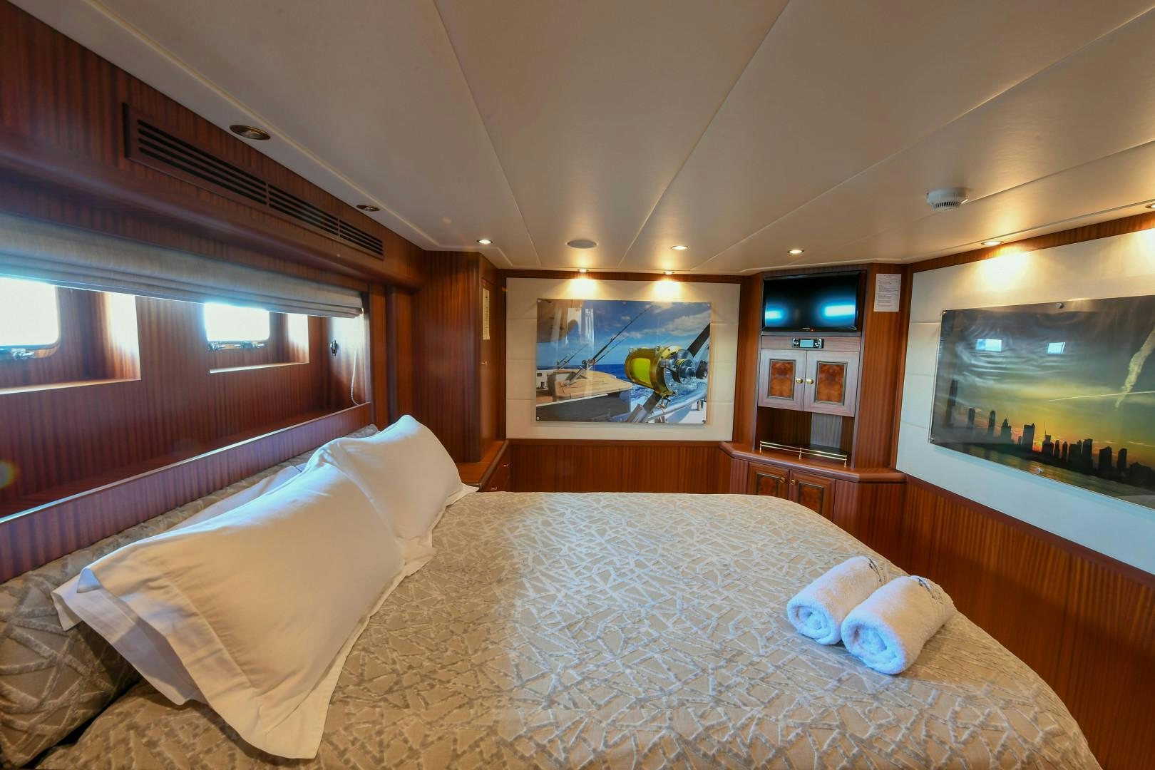 a bed with a white sheet and pillows in a room with a television aboard LITTLE BLUE Yacht for Sale