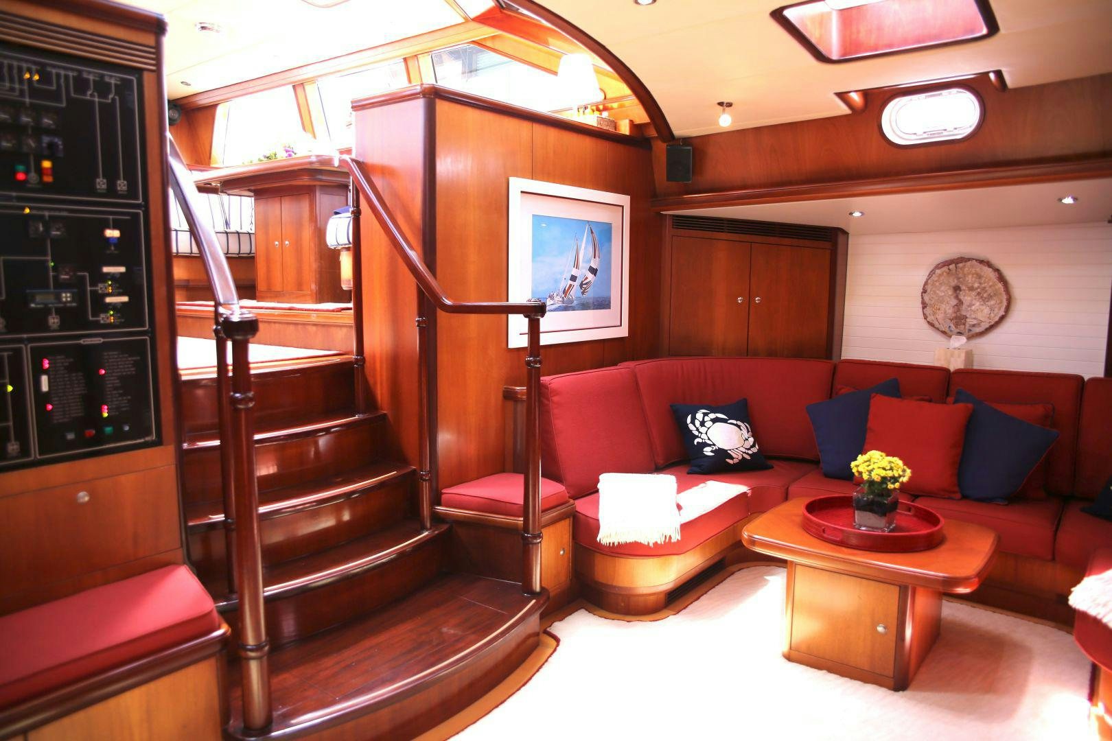 a living room with a red couch and a wood staircase aboard WHIRLWIND Yacht for Sale