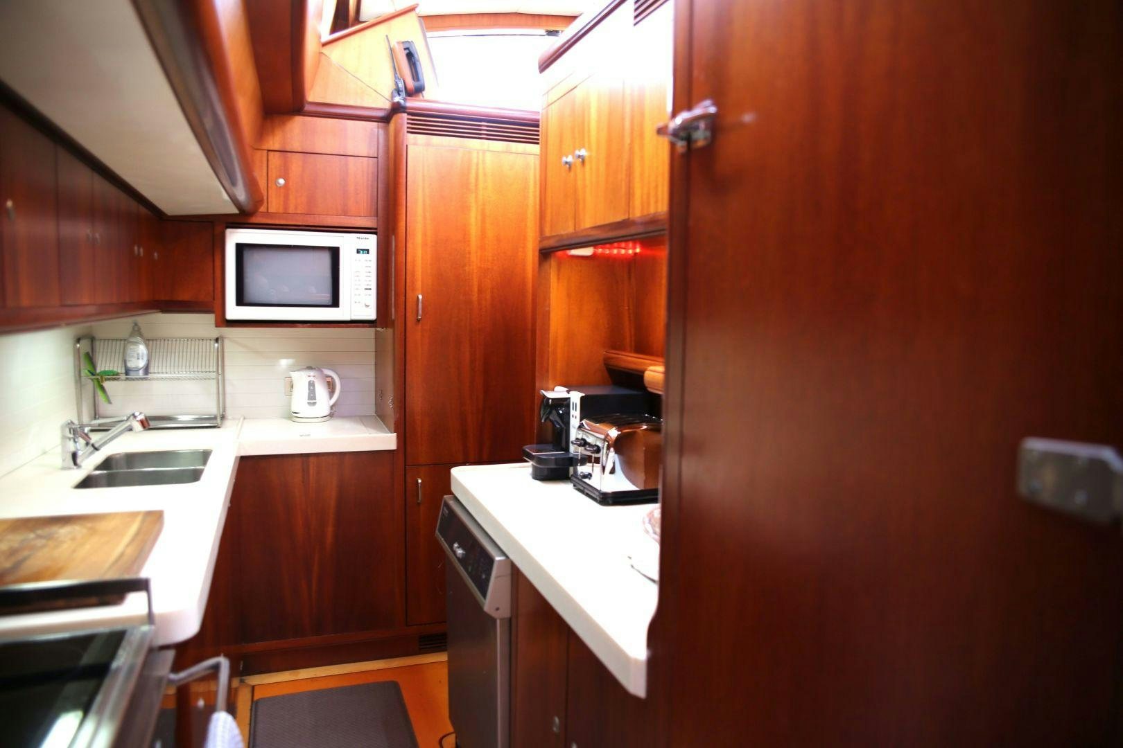 a small kitchen with wooden cabinets aboard WHIRLWIND Yacht for Sale