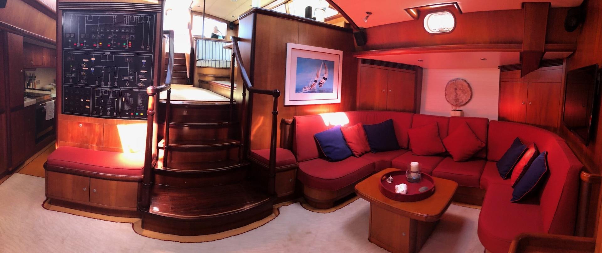 a living room with a red couch and a staircase aboard WHIRLWIND Yacht for Sale