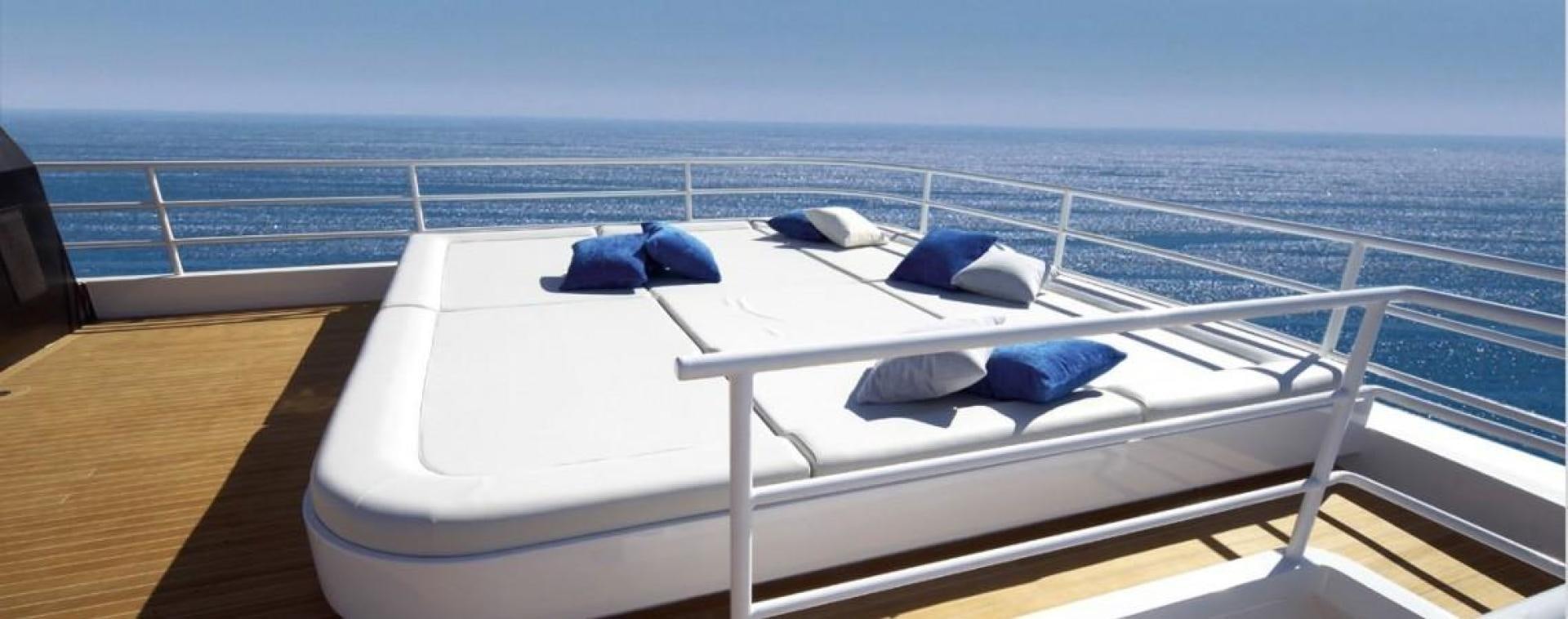 a white boat with blue pillows on a deck with a blue hat on it aboard NO NAME Yacht for Sale