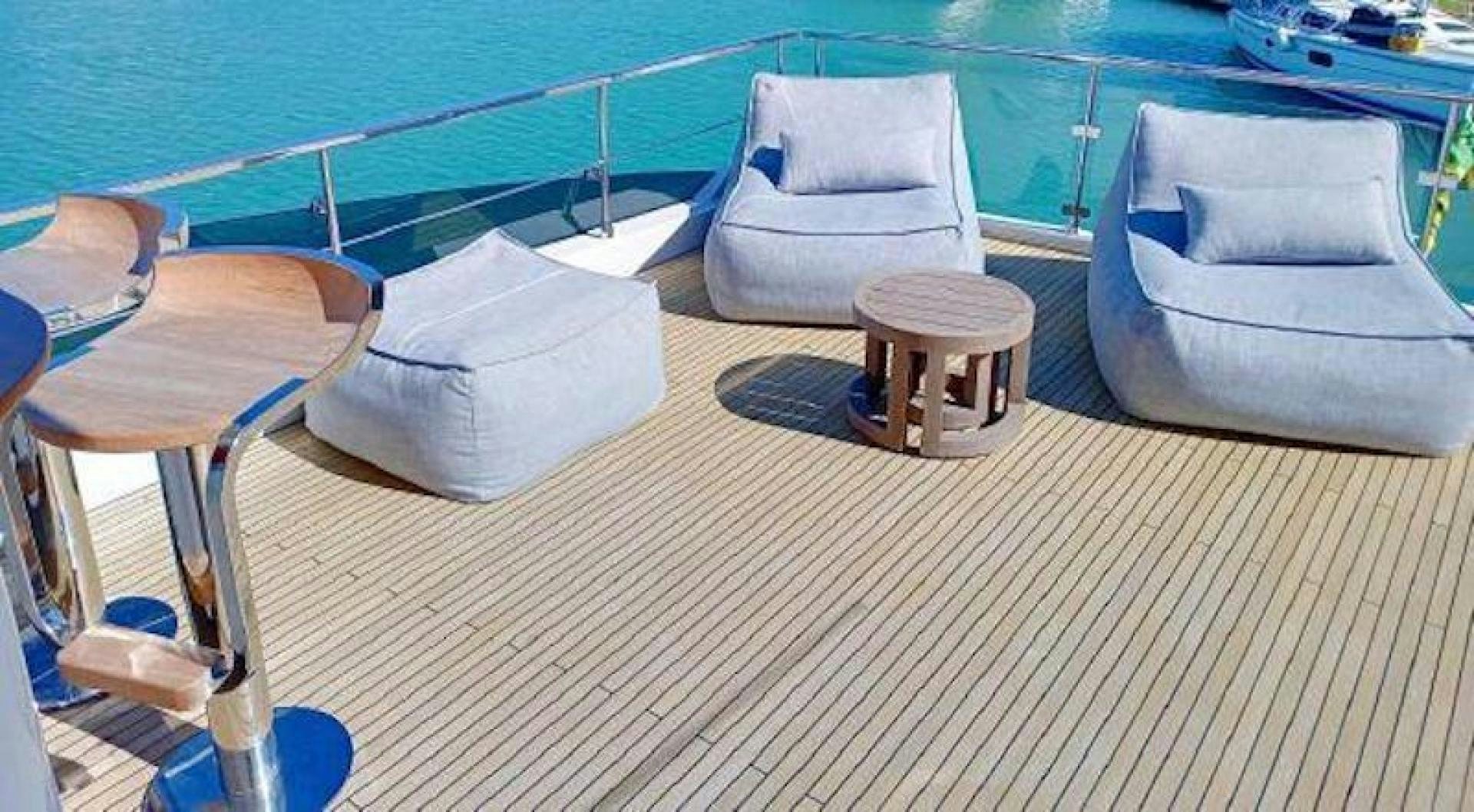 a deck with chairs and a table on it aboard NOMAD Yacht for Sale