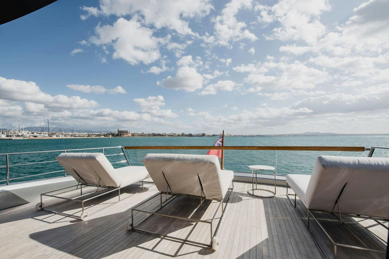 a deck with chairs and a body of water in the background aboard ZAZZAZU II Yacht for Sale