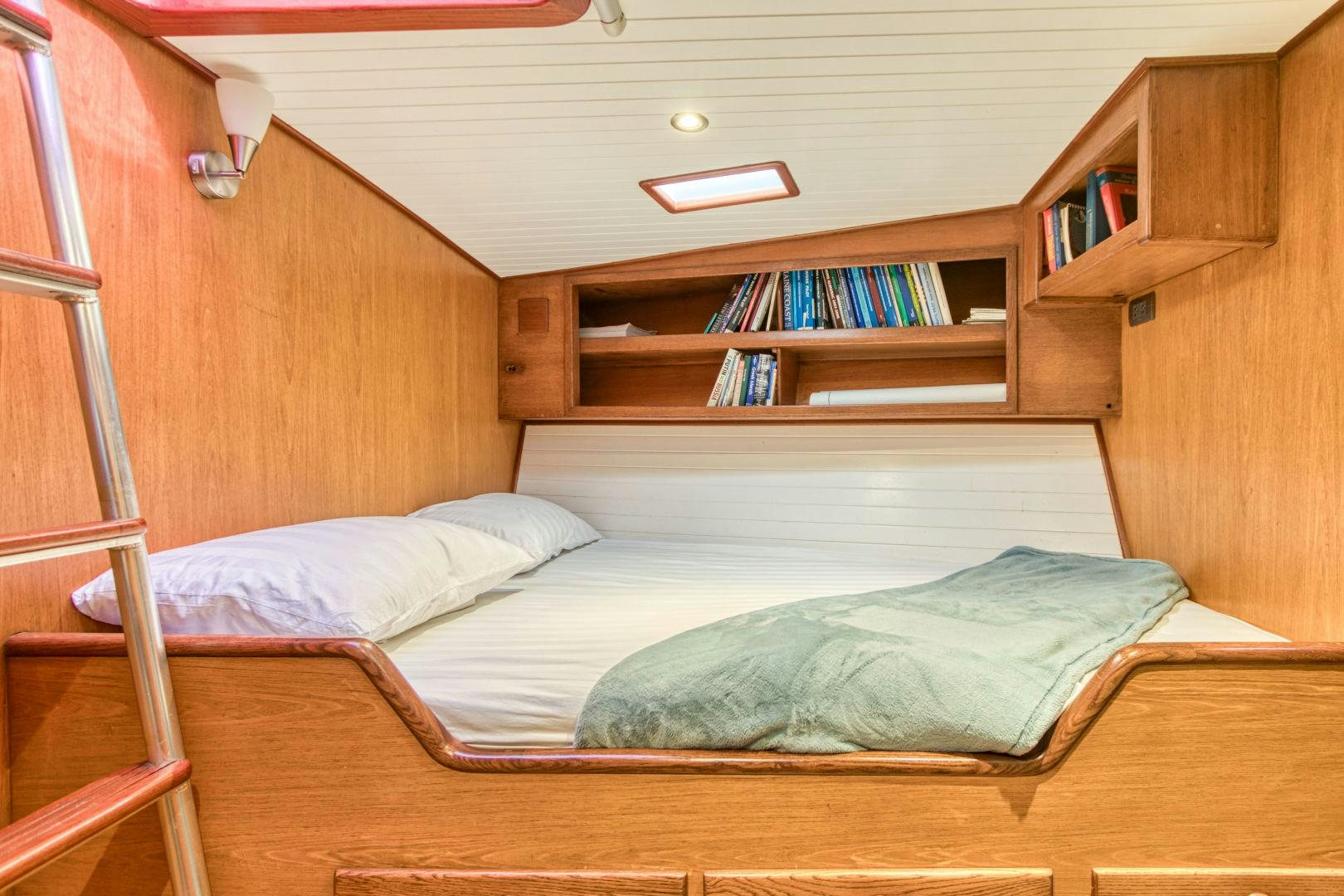 a bed with a bookcase and a shelf with books aboard ARIA Yacht for Sale
