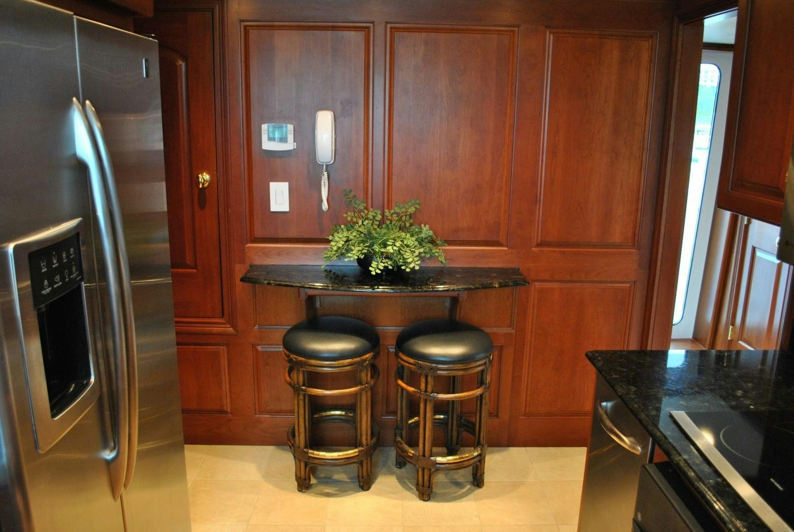 a kitchen with a refrigerator and stools aboard JENNY LYNNE Yacht for Sale