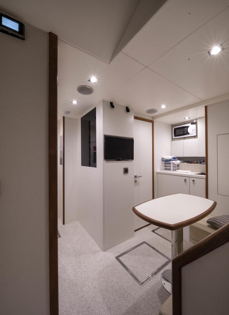 a kitchen with a table and a tv on the wall aboard PURA VIDA Yacht for Sale