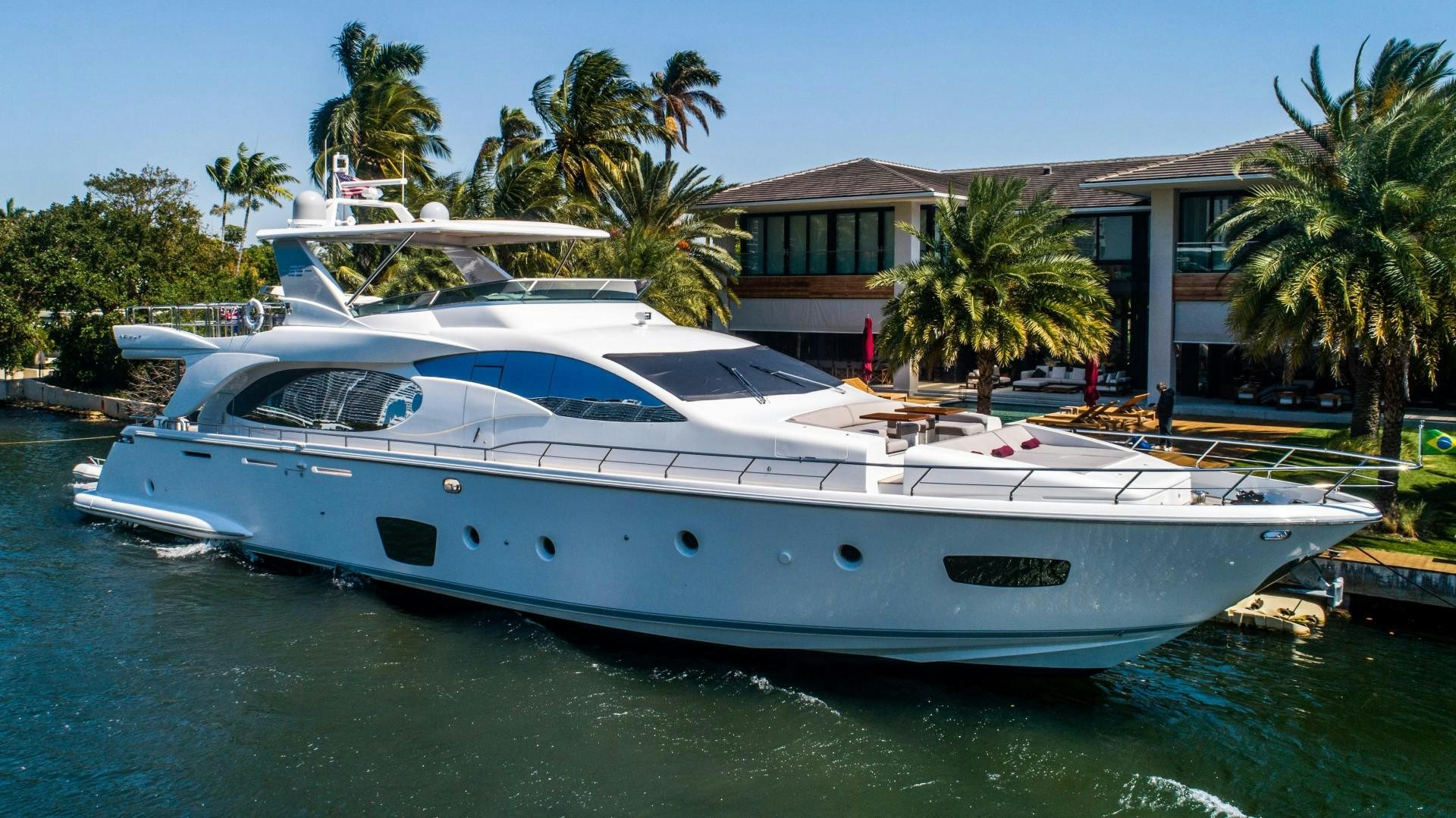 a white yacht docked in front of a house aboard Blue Yacht for Sale