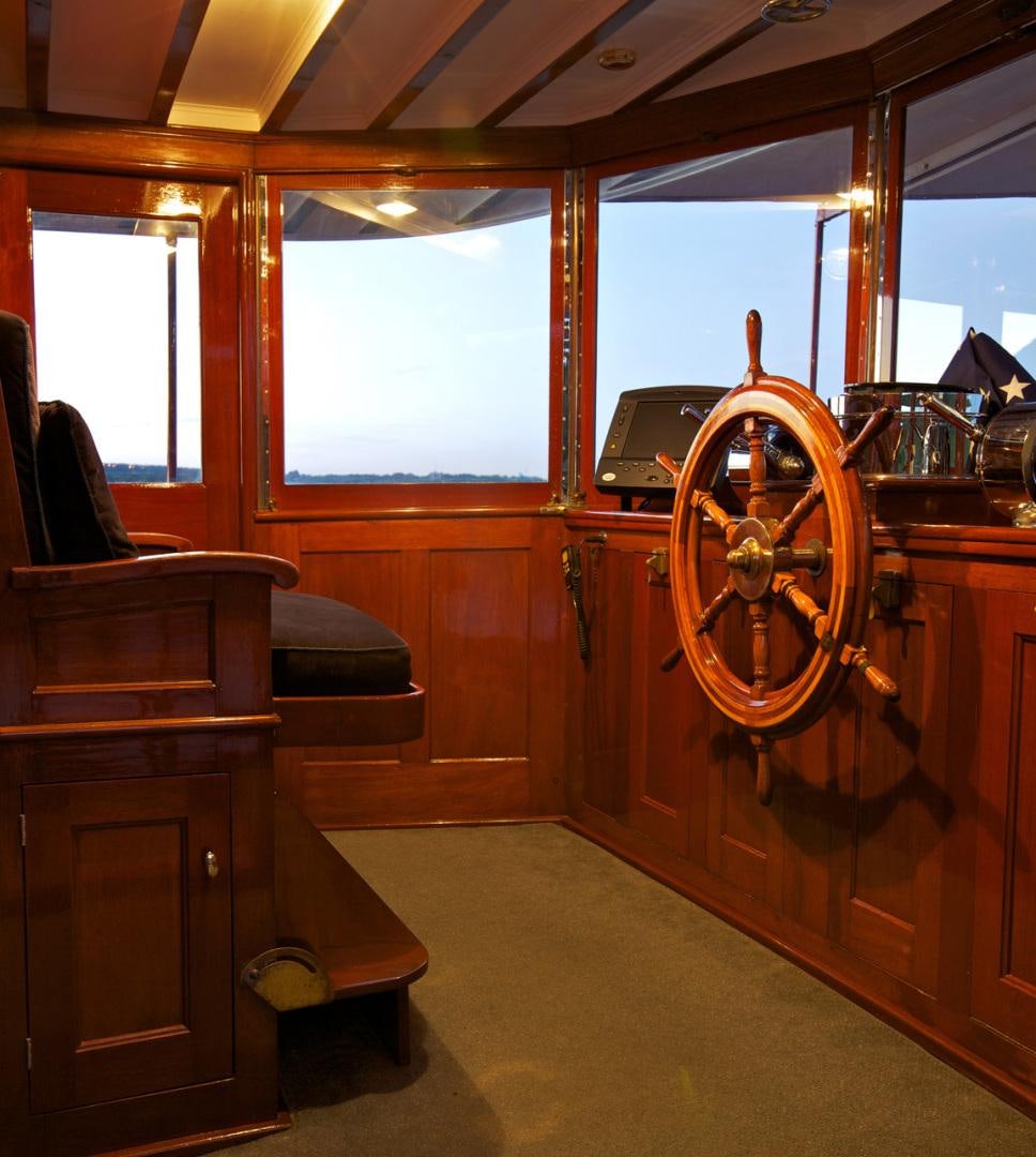 a large wooden boat with a steering wheel and wooden seats aboard ENTICER Yacht for Sale