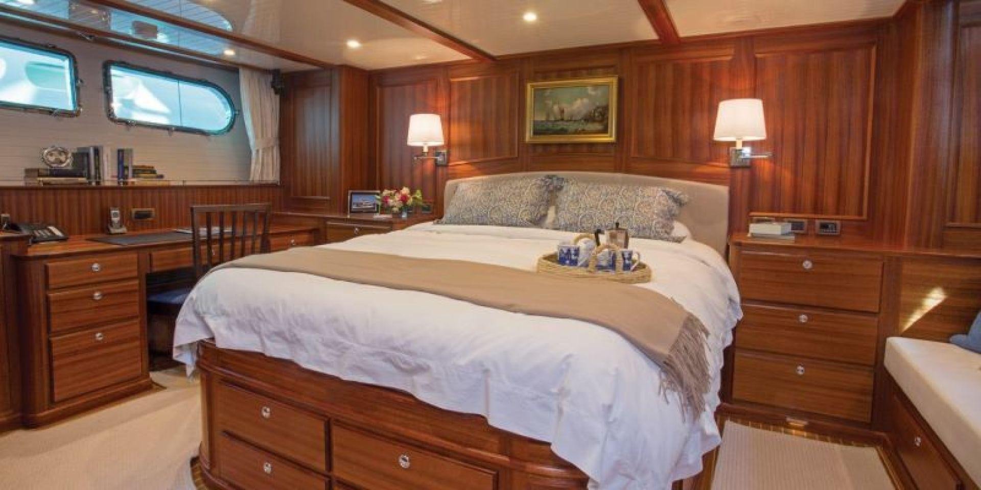 a bedroom with a bed and a dresser aboard OCEAN 76 Yacht for Sale