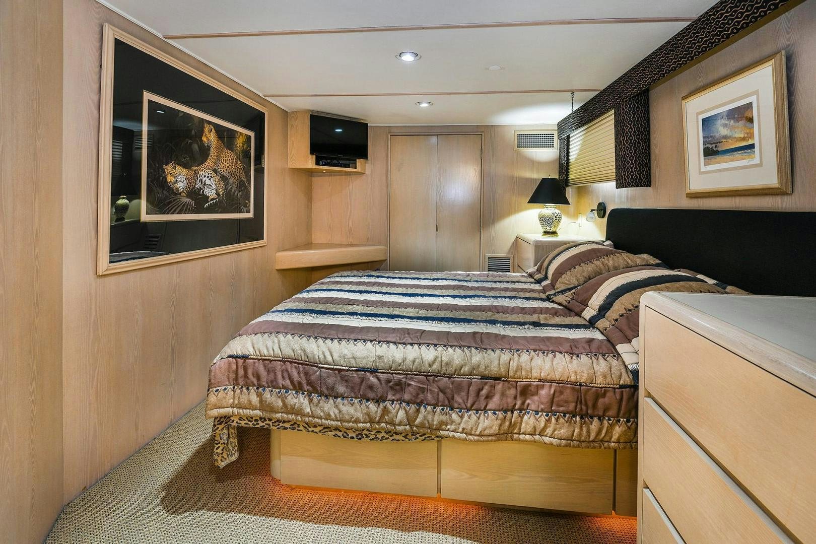 a bedroom with a bed and a painting on the wall aboard PRIMETIME III Yacht for Sale
