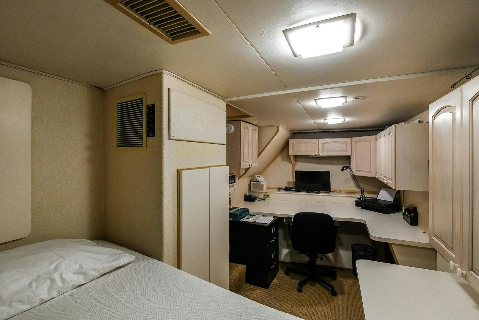 a bedroom with a bed and desk aboard PRIMETIME III Yacht for Sale