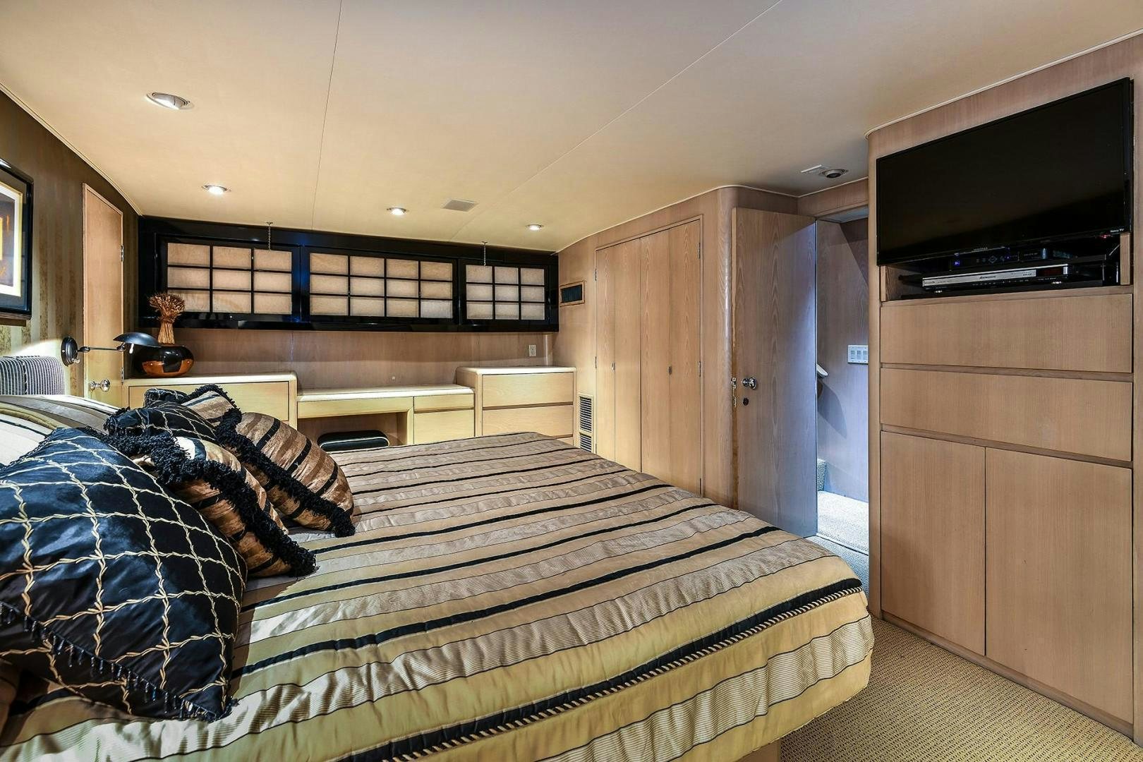 a bedroom with a bed and a tv aboard PRIMETIME III Yacht for Sale