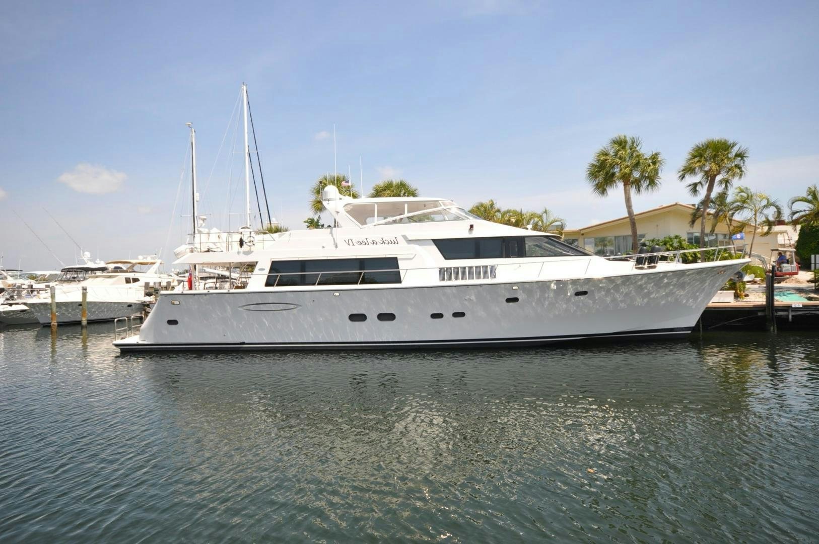 a white yacht in a harbor aboard LUCK A LEE IV Yacht for Sale