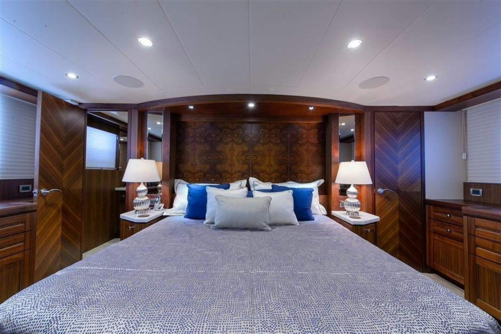 a bed with a blue and white pillow and a wooden headboard aboard OCEANA Yacht for Sale