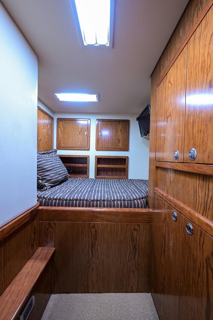 a bedroom with a bed and a wood cabinet aboard BLACK SHADOW Yacht for Sale
