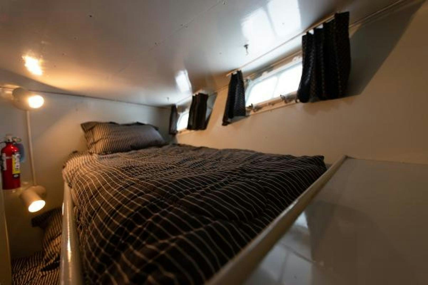 a bed with a black and white comforter and a black curtain aboard No Name Yacht for Sale