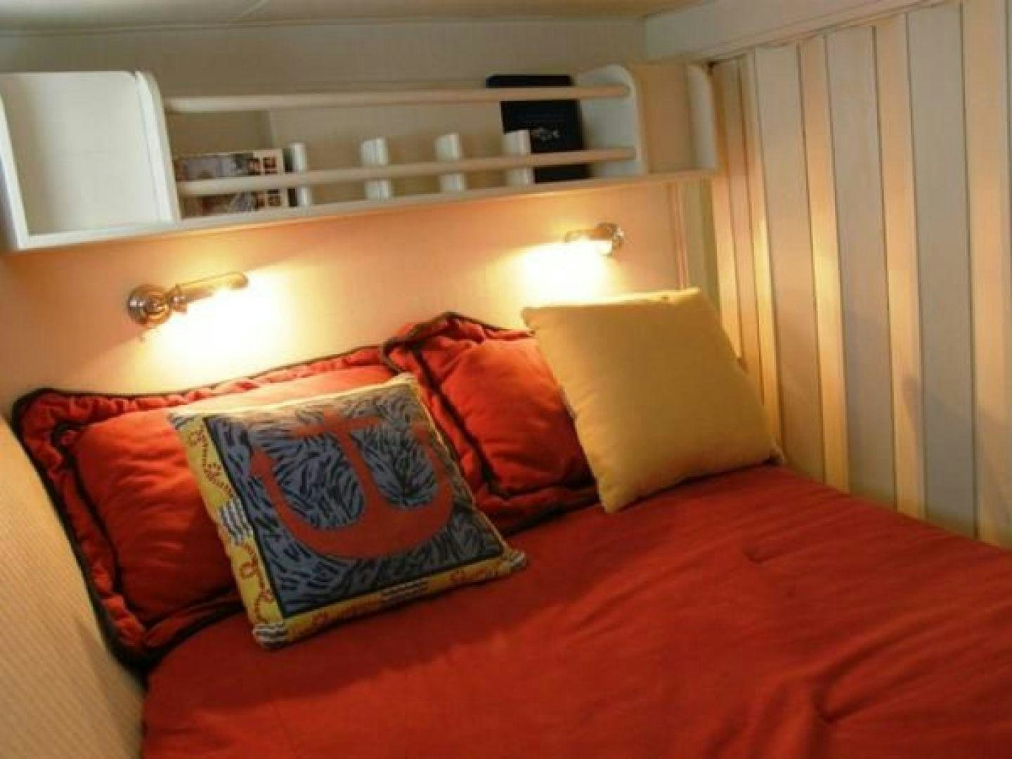 a bed with orange pillows aboard HIGH MILEAGE Yacht for Sale