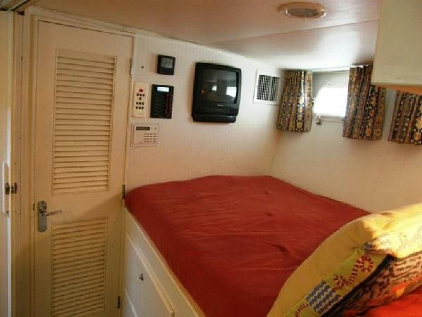 a bedroom with a bed and a television on the wall aboard HIGH MILEAGE Yacht for Sale