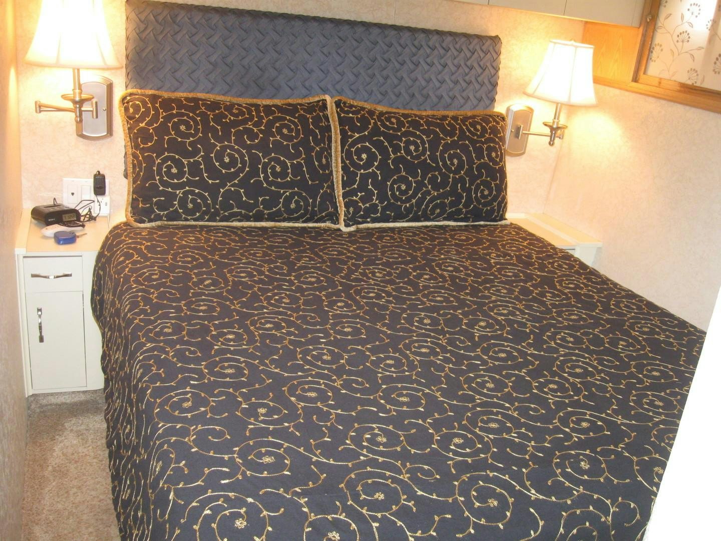 a bed with a black and white comforter and a lamp on the side aboard OCEAN ROMANCE Yacht for Sale
