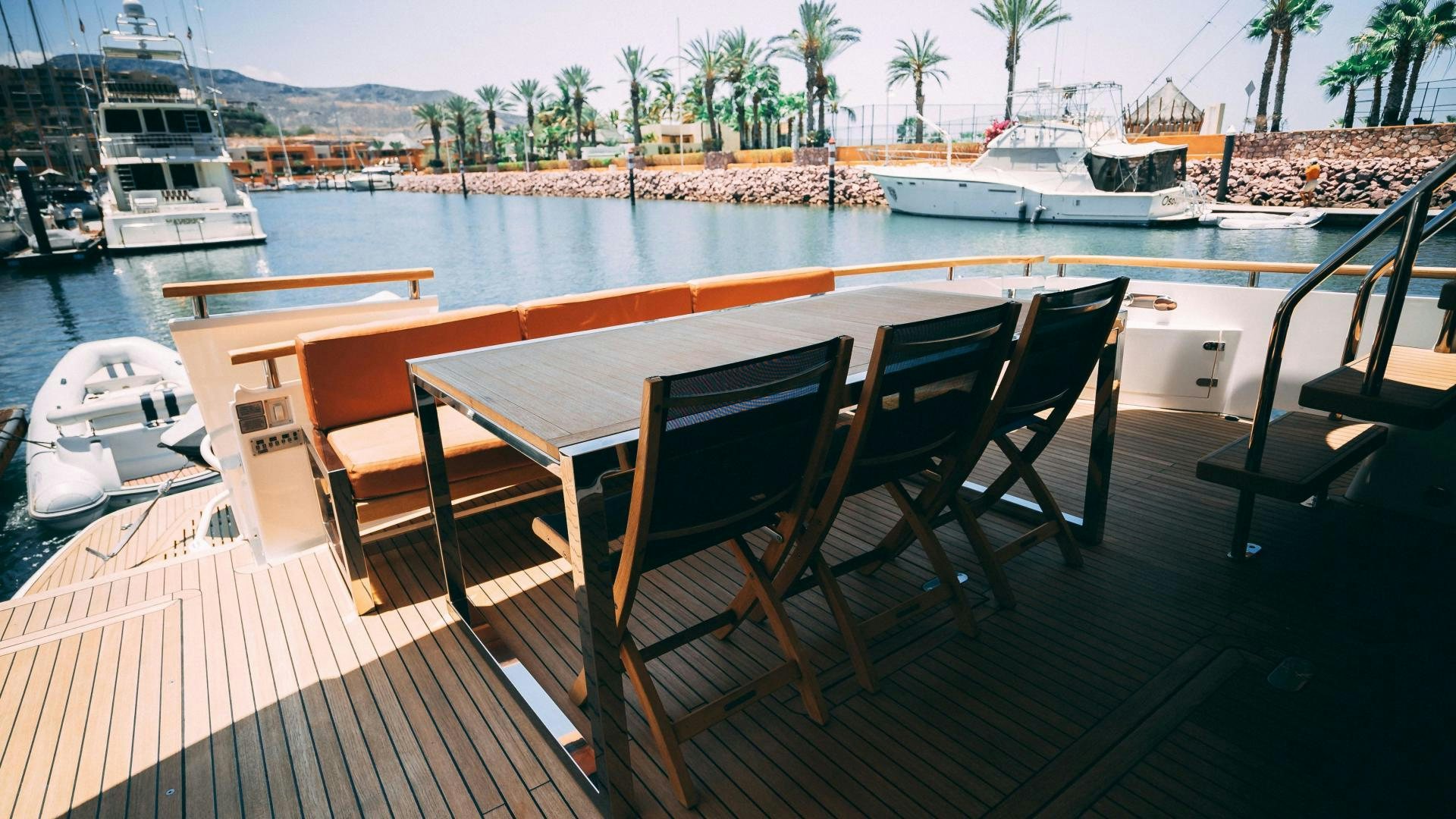 a deck with chairs and a table on it by a body of water aboard OCHO UNO Yacht for Sale