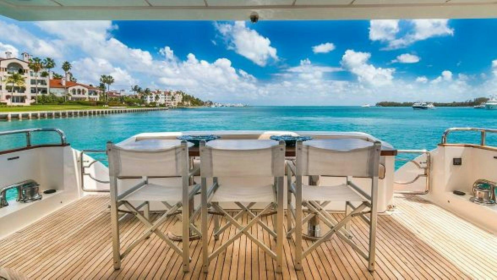 a table and chairs on a deck overlooking a body of water aboard NO LIMITS Yacht for Sale