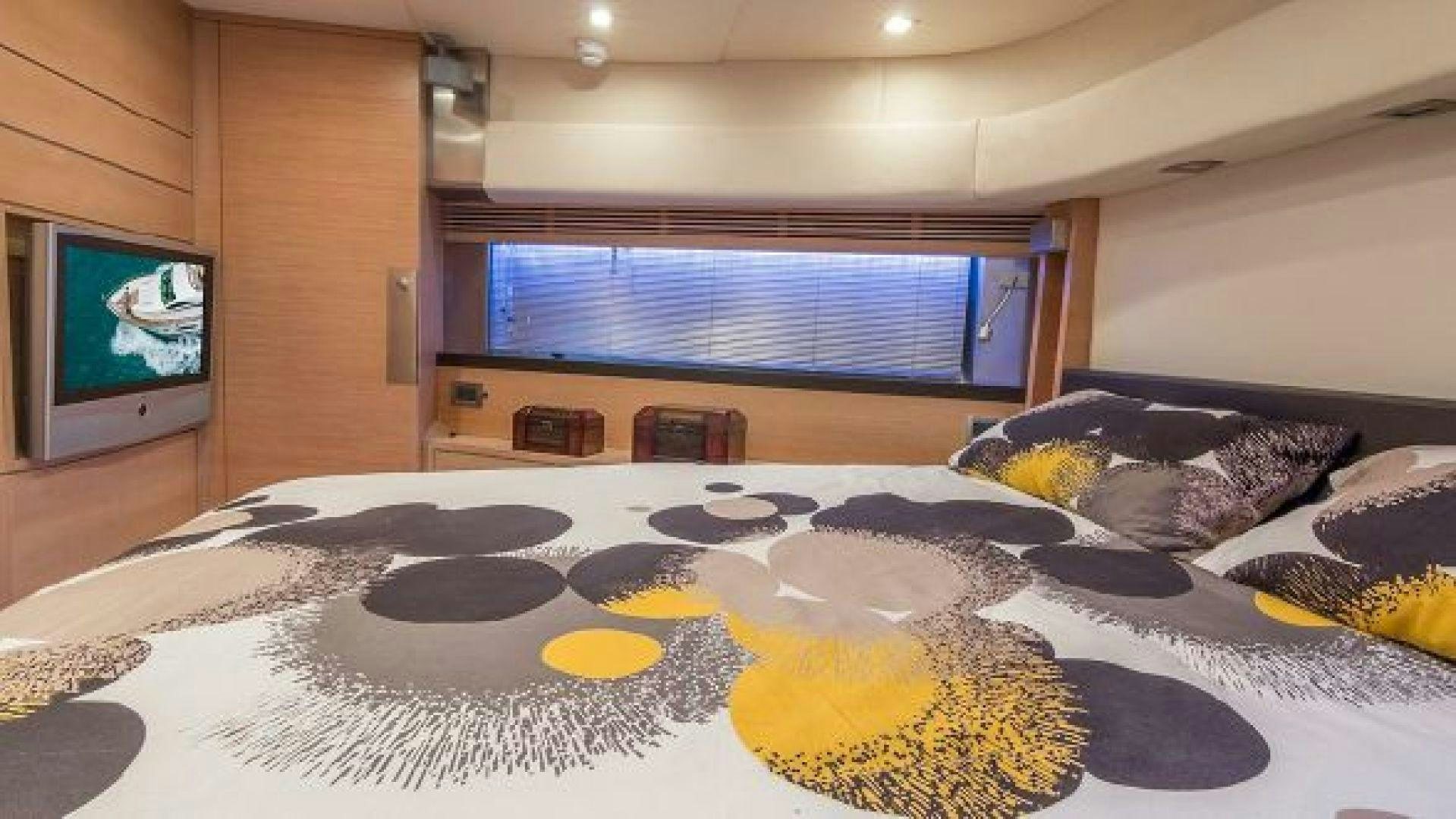 a bed with a television on the wall aboard NO LIMITS Yacht for Sale