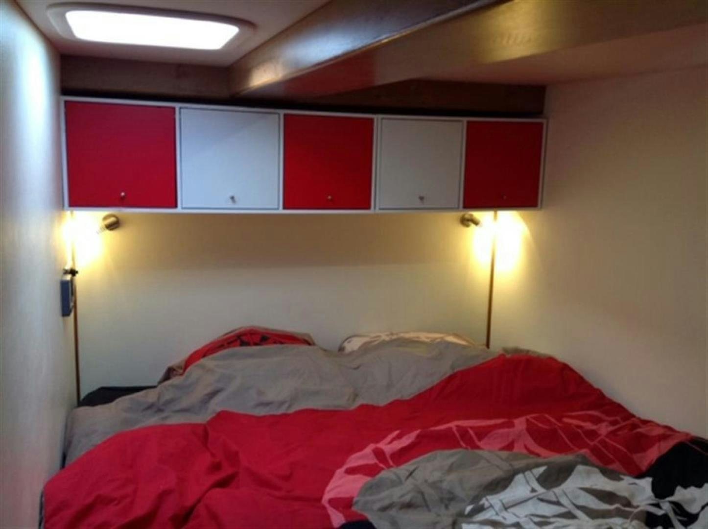 a room with a bed and a red wall aboard HELICAT RED Yacht for Sale