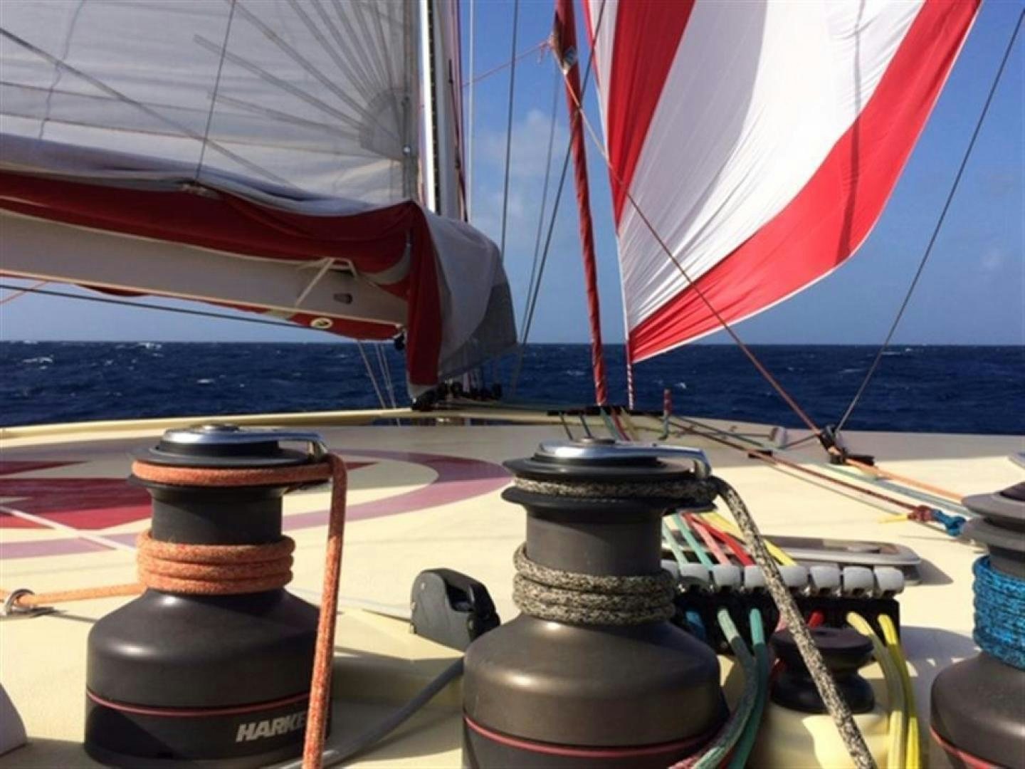 a red and white sailboat on a sunny day aboard HELICAT RED Yacht for Sale