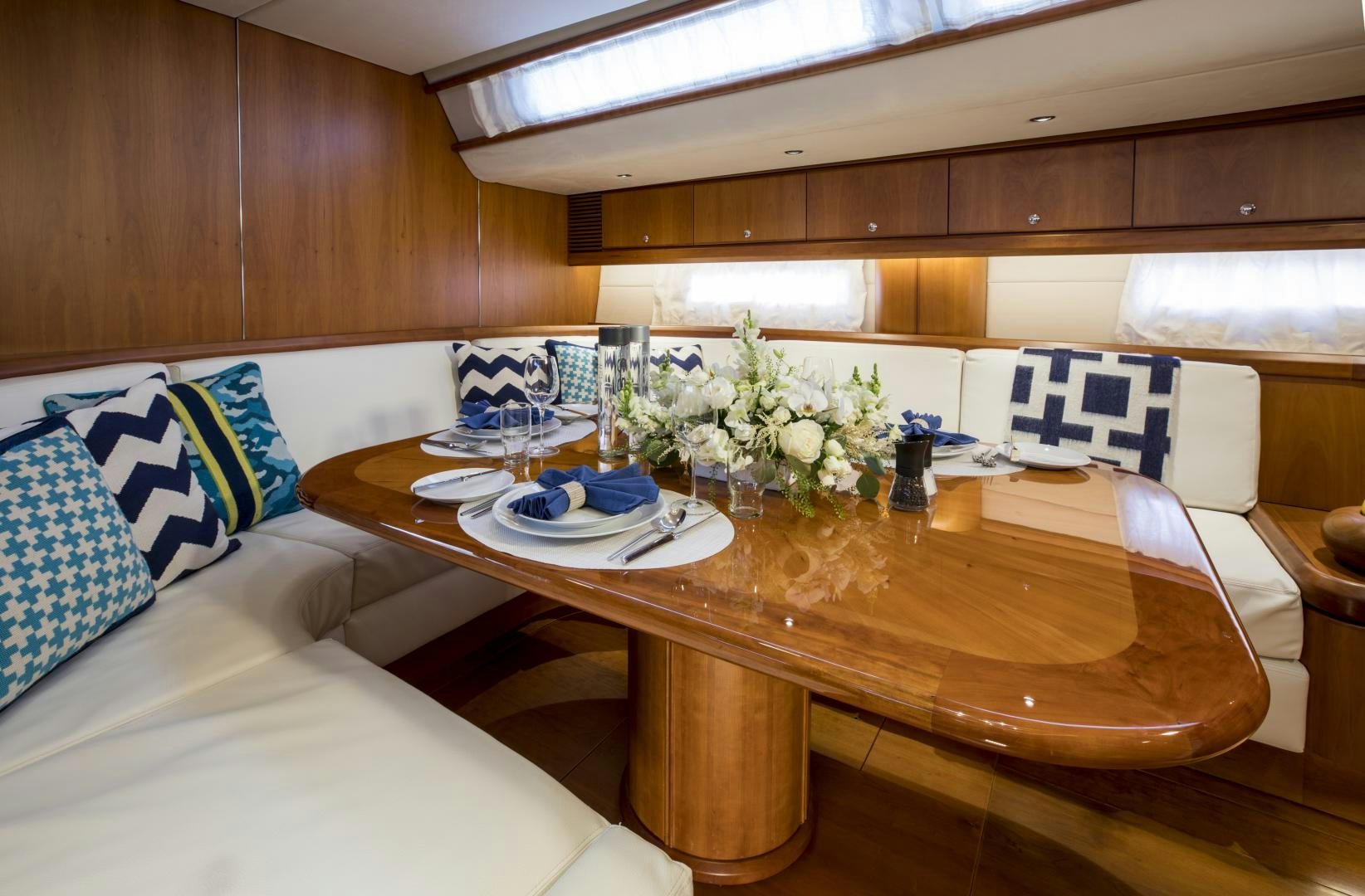 a table with a flower vase and a bed in a room aboard aglaia Yacht for Sale