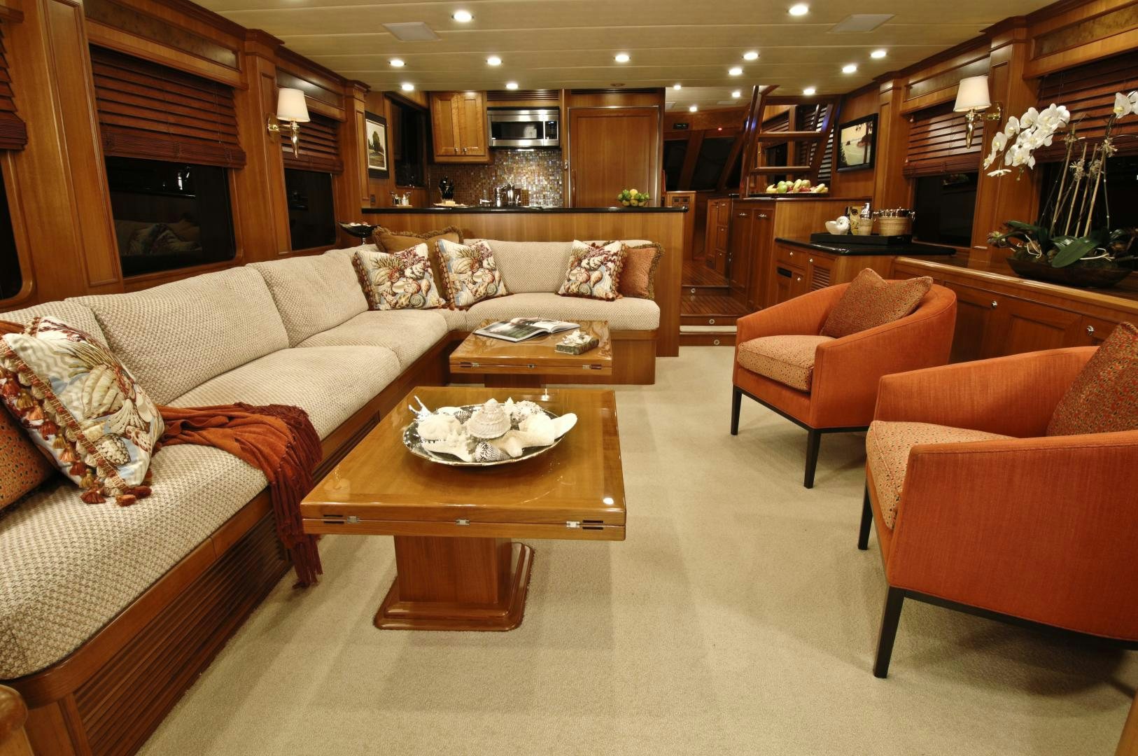 a living room with orange couches and a coffee table aboard No Name Yacht for Sale