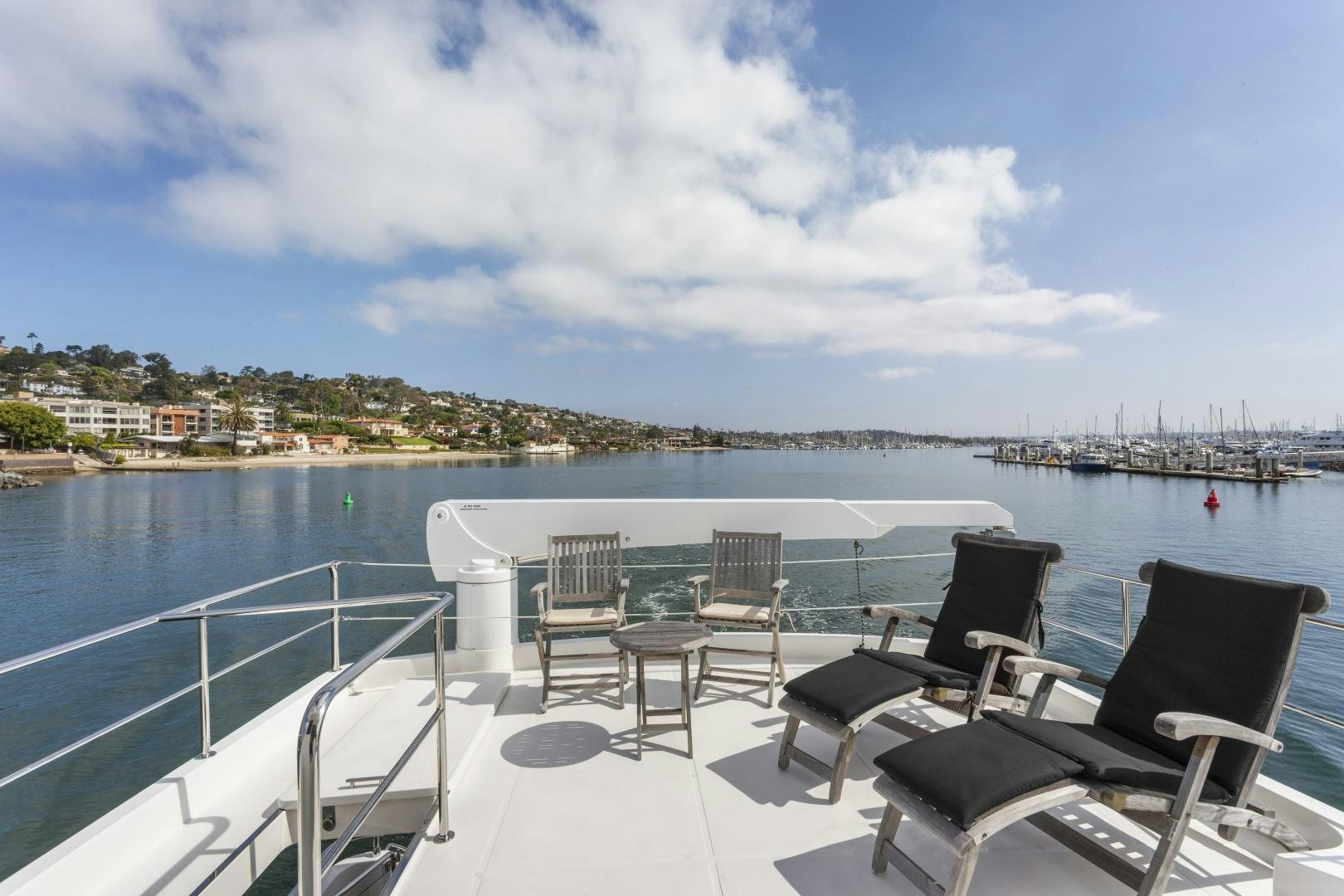 a deck with chairs and tables on it by a body of water aboard ODYSEA Yacht for Sale