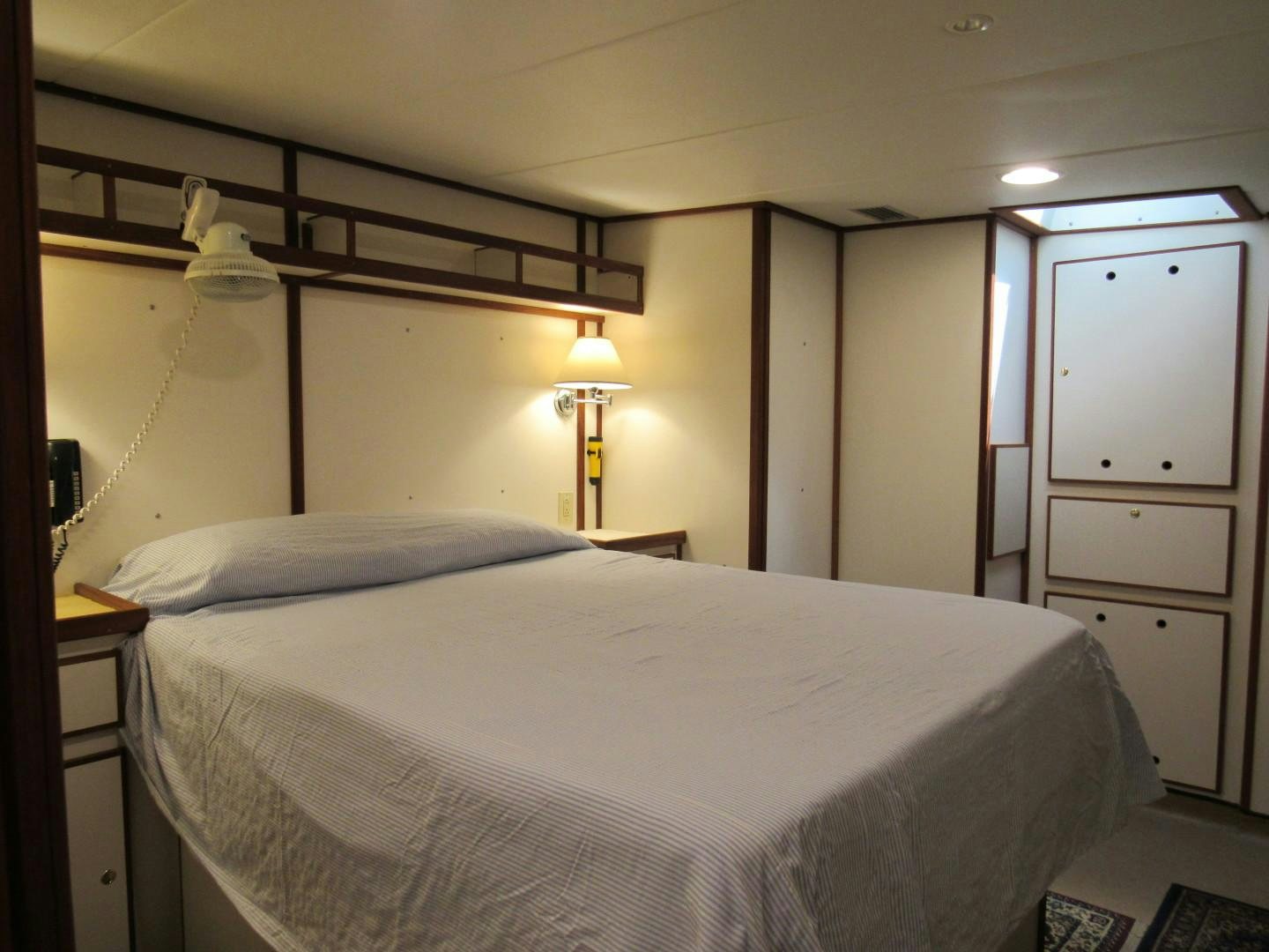 a bedroom with a bed and a lamp aboard KITTIWAKE Yacht for Sale