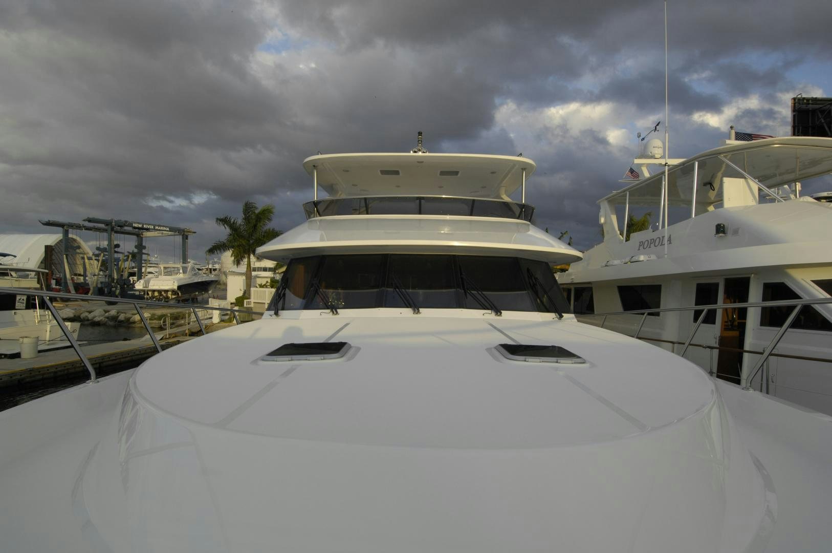 a white yacht in a harbor aboard HATT TRICK Yacht for Sale