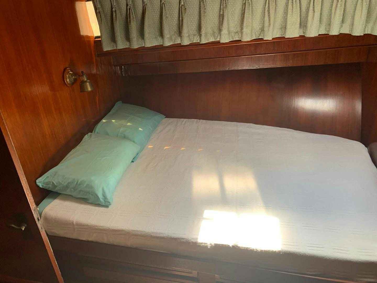 a bed with a white sheet and a blue pillow on it aboard No Name Yacht for Sale