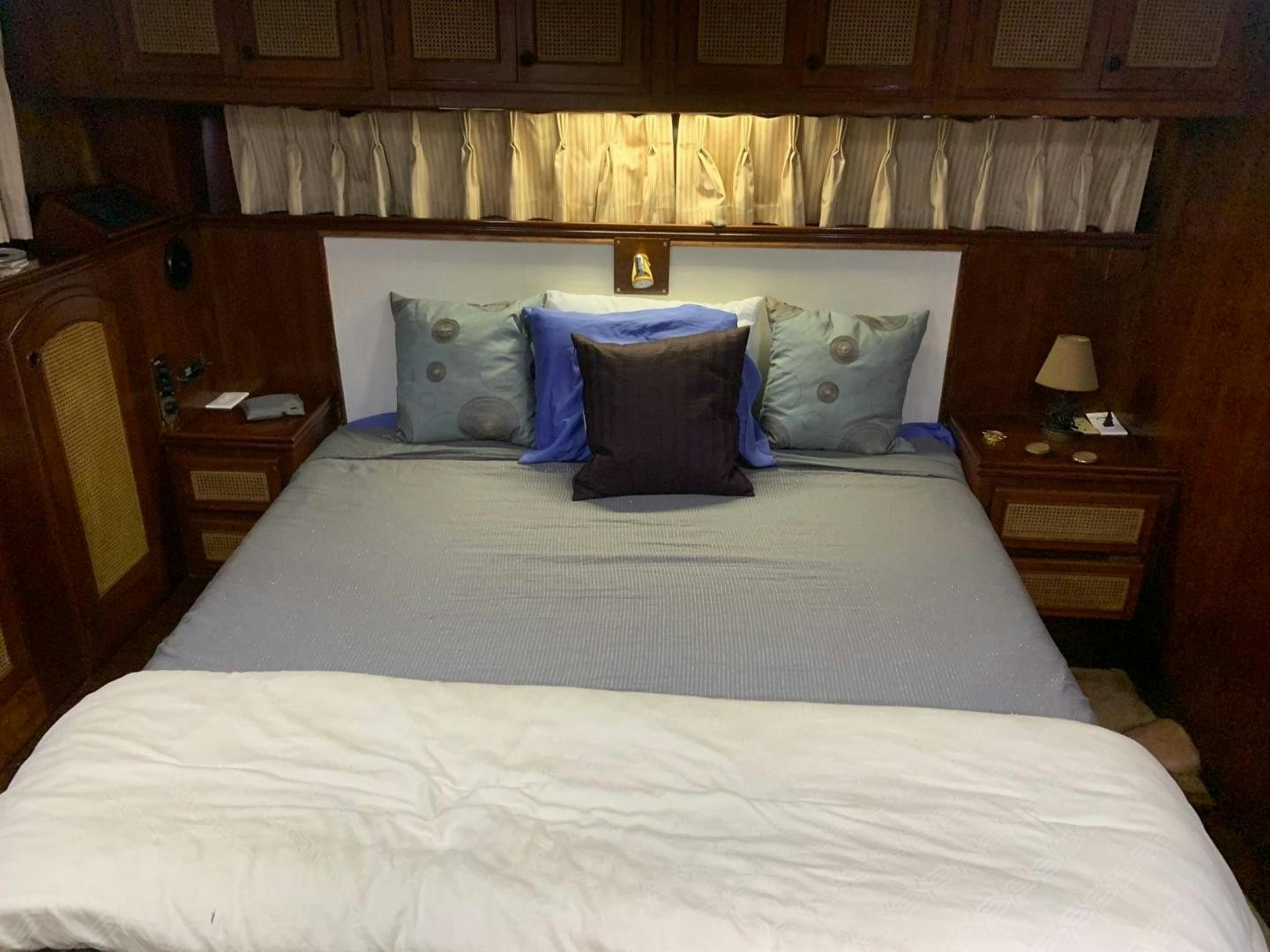 a bed with a white comforter and blue pillows aboard No Name Yacht for Sale