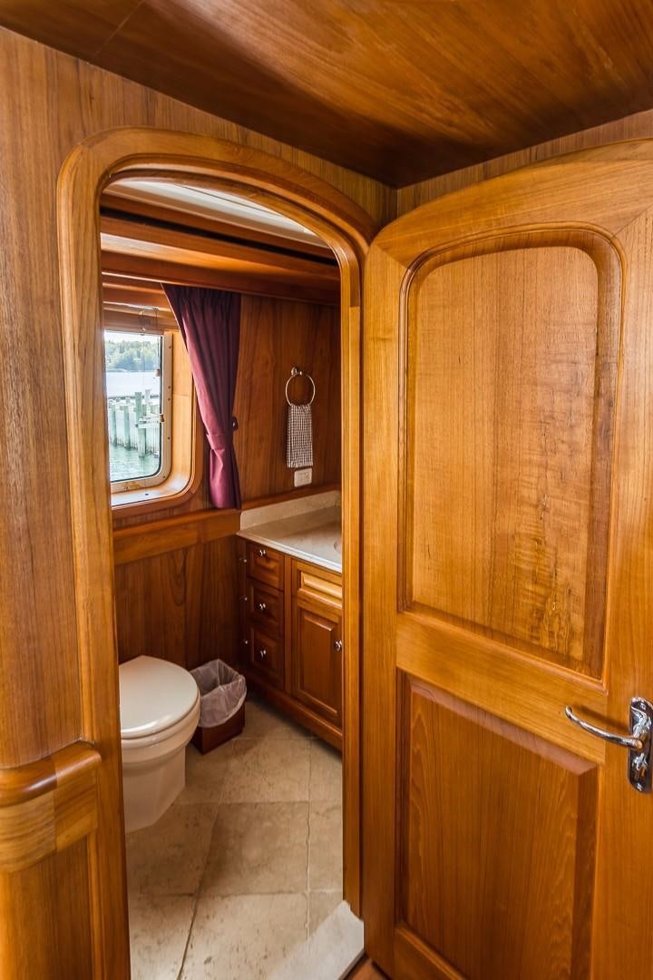 a bathroom with a toilet and a wooden cabinet aboard HERCULES Yacht for Sale