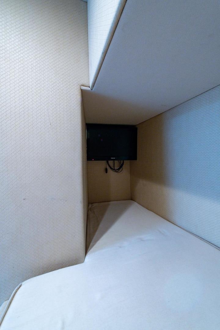 a bed with a television on the wall aboard SOMEWHERE I BELONG Yacht for Sale
