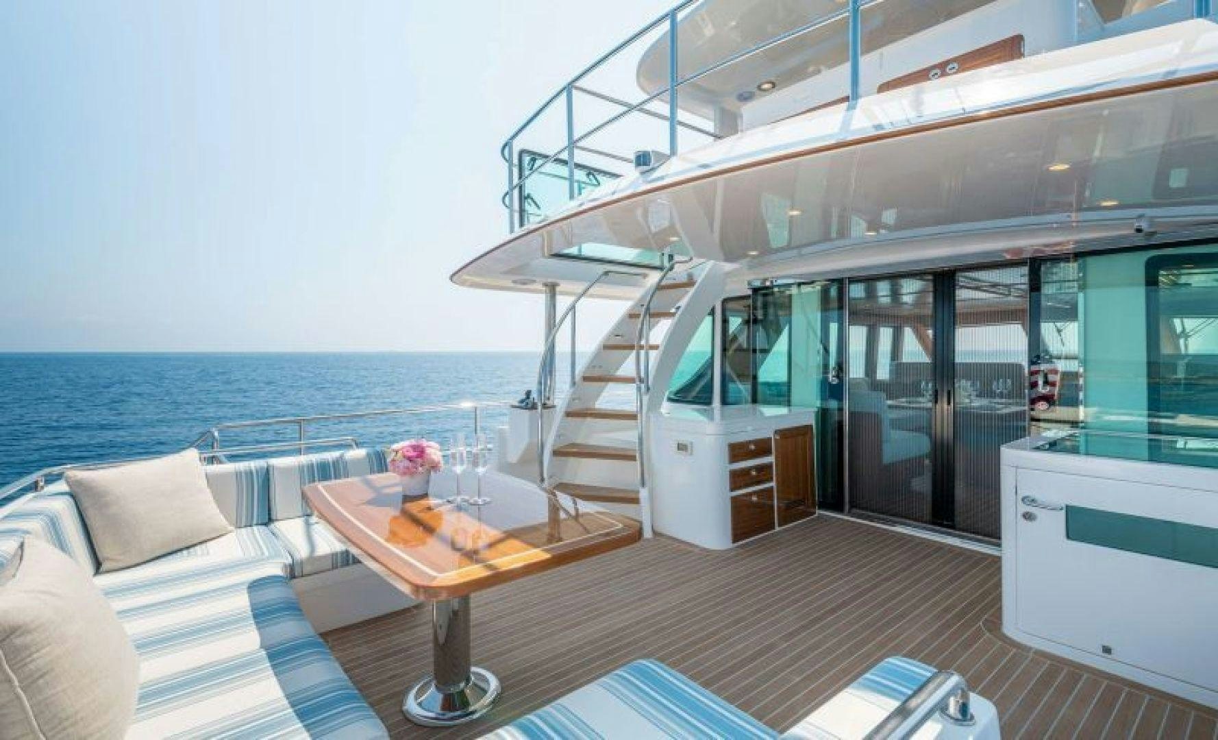 a room with a table and a couch and a large window aboard OCEAN 63 Yacht for Sale