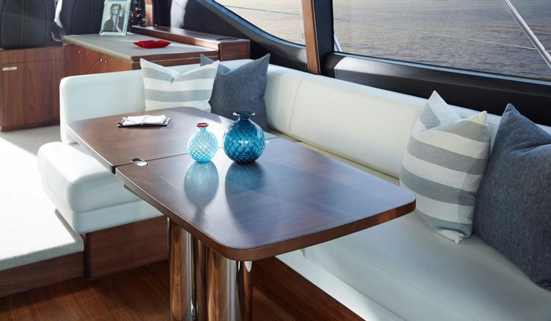 a white couch with pillows and a coffee table in a room with a window and wood cabinets aboard Namaste Yacht for Sale