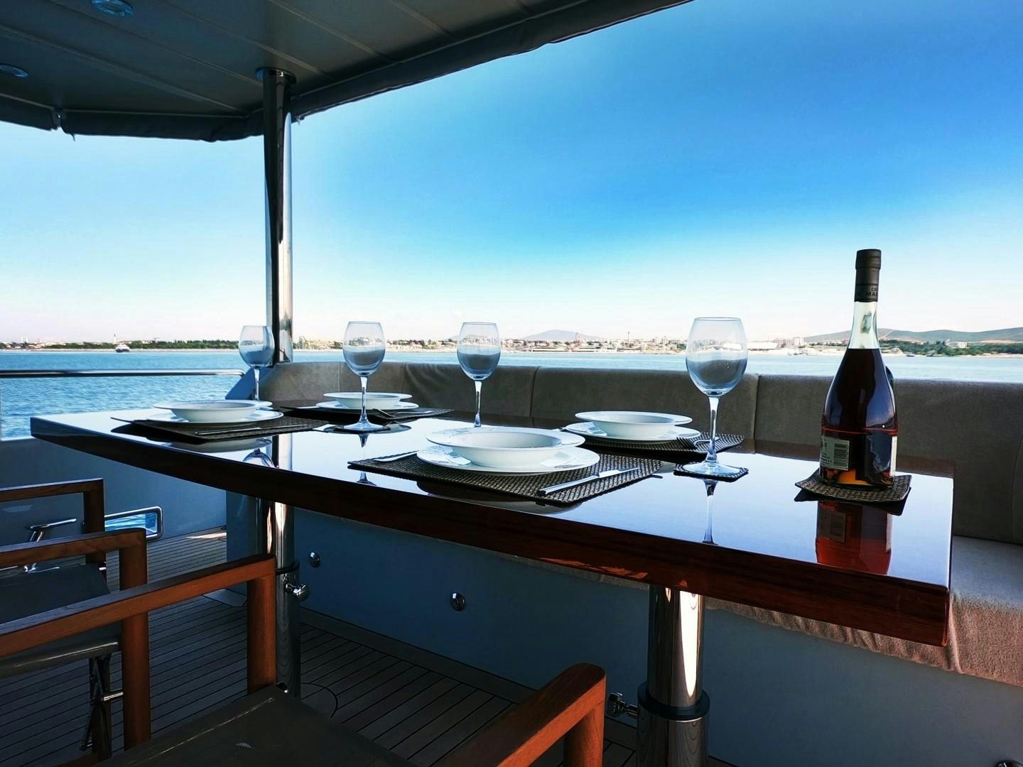 a table with wine glasses and plates on it aboard MUZO'S 20 Yacht for Sale