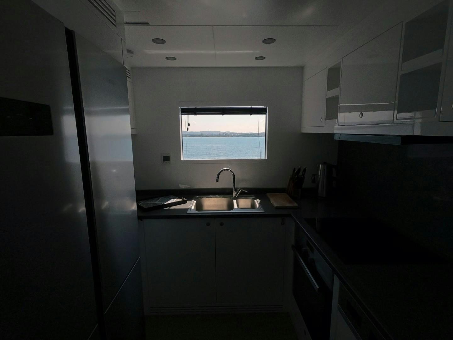 a small kitchen with a sink and refrigerator aboard MUZO'S 20 Yacht for Sale