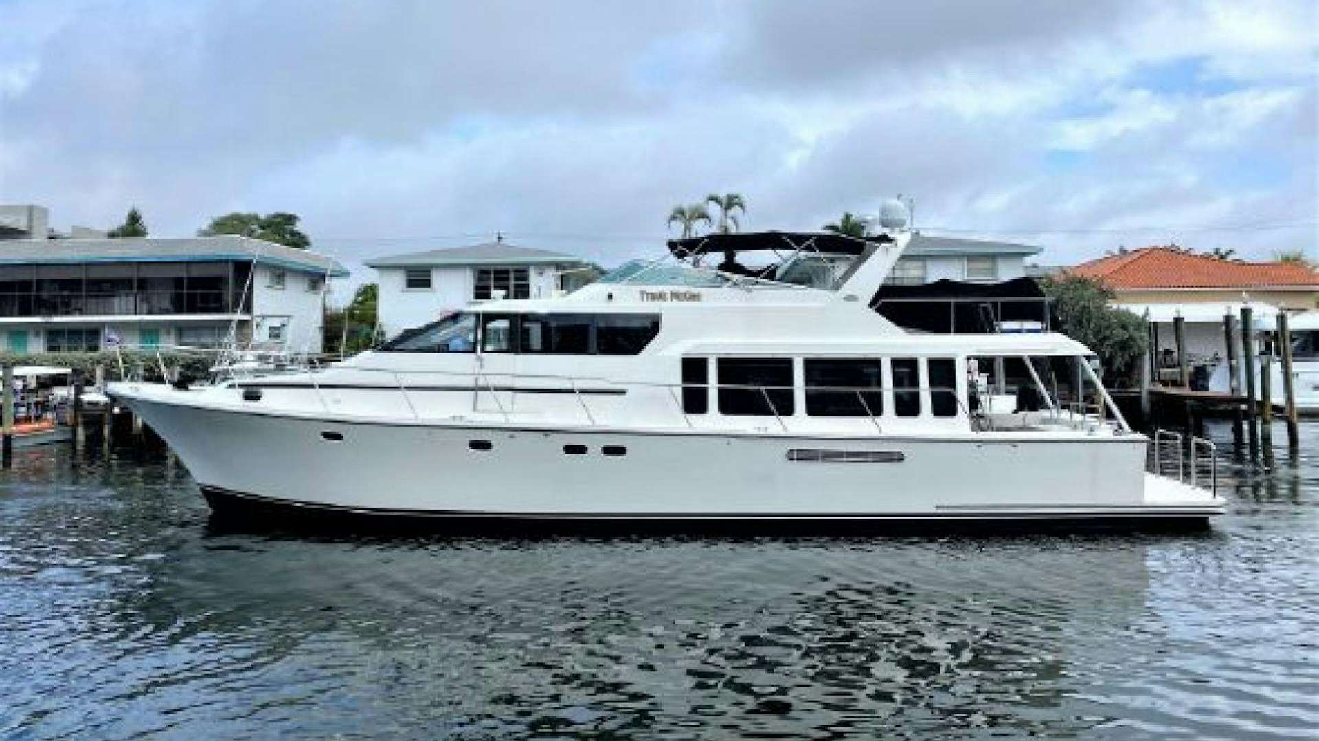 a white boat in a harbor aboard TRAVIS MCGEE Yacht for Sale