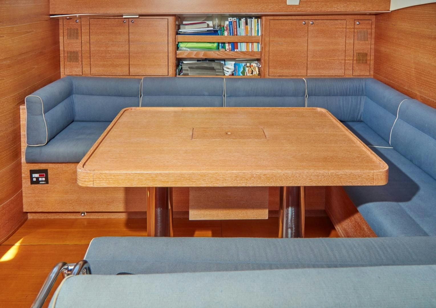 a table with a couch in a room with books on shelves aboard SPIRIT OF ALTAIR Yacht for Sale