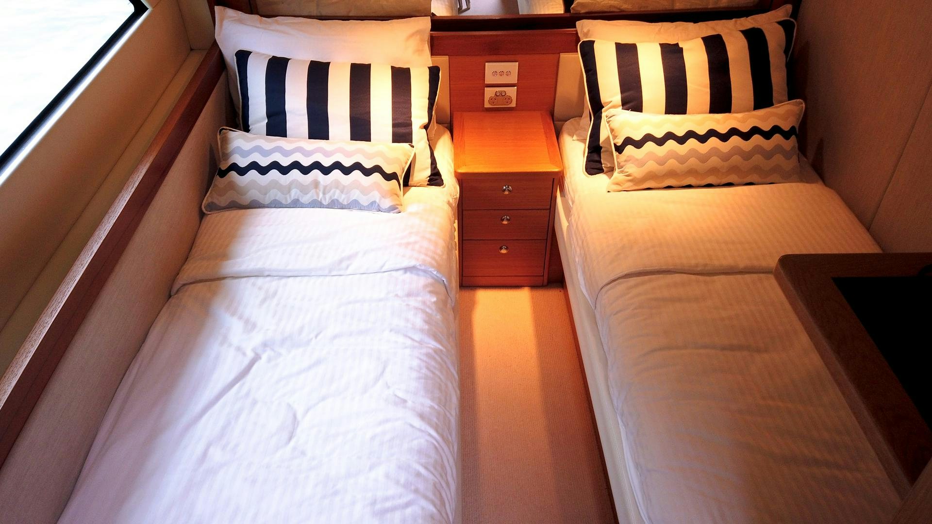 a bed with a white and orange pillow and a white bed spread aboard SURVIVOR Yacht for Sale