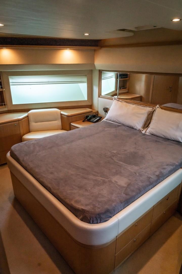 a bed with a chair and a window aboard FORTIS II Yacht for Sale