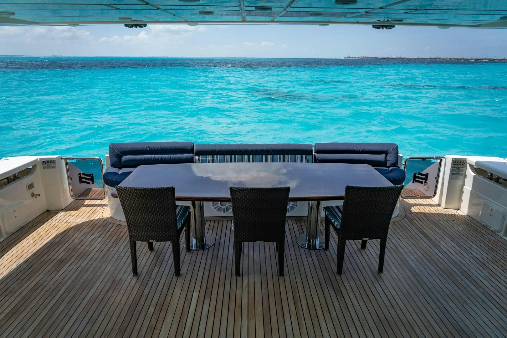 a table and chairs on a deck overlooking a body of water aboard FORTIS II Yacht for Sale